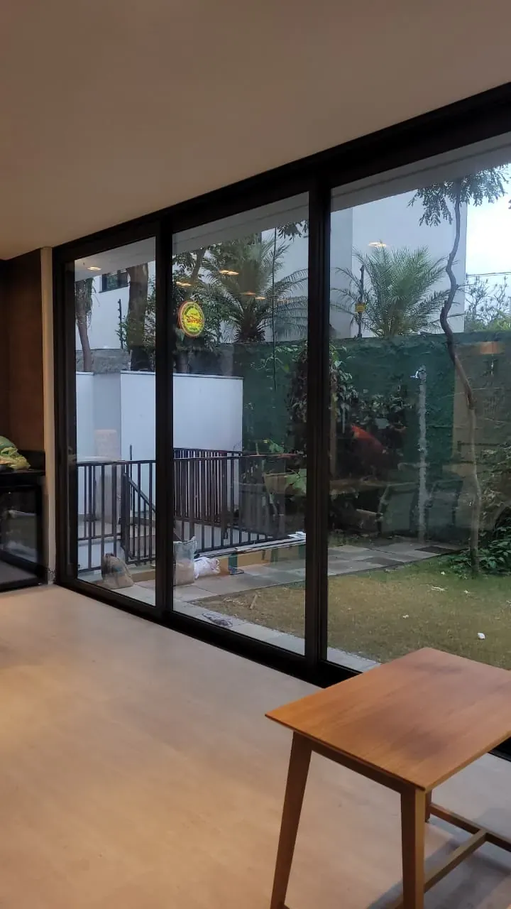Porta de vidro de sala com película de controle solar e vista para o jardim